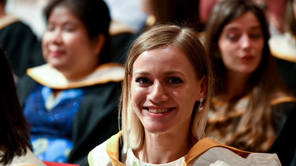 A student at an RCM graduation ceremony smiling at the camera
